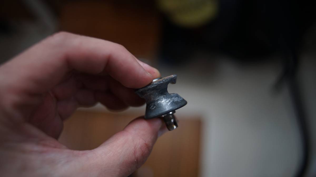 a hand holding a sheave which has been dug into over a long period of time by a rope wire