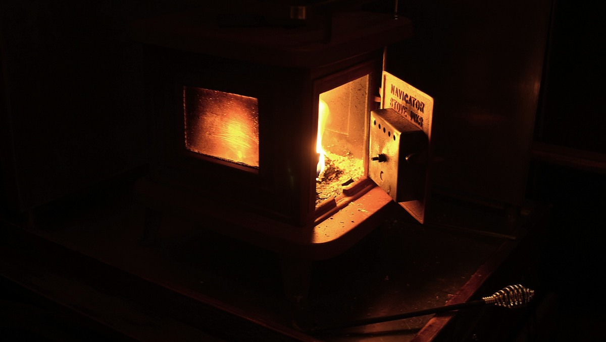flame burning inside wood stove A photo of a sardine woodstove with a small fire roaring inside its belly