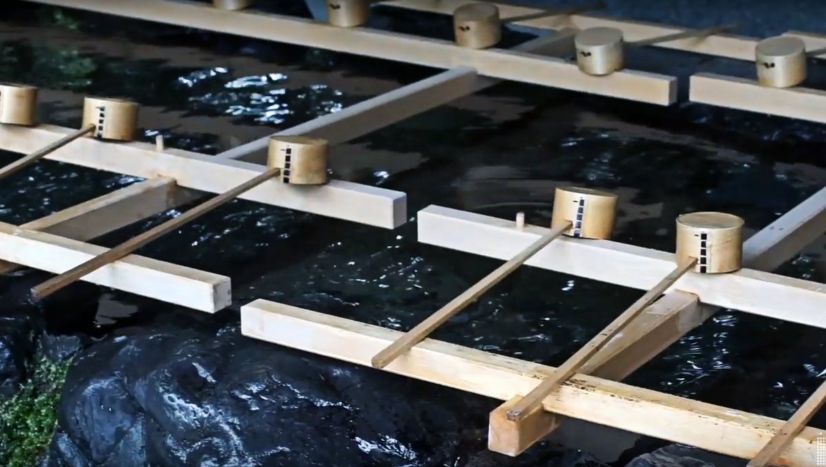 Temizusha a photo of a Temizusha, a series of wooden ladles sit over a basin of fresh water