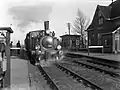 Steam locomotive no. 7008 (series 7000) of the NS with carriages along the platform of the Bovenkerk station.