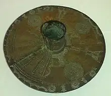 Anklet beaten from a solid brass bar of the type worn by Igbo women. Now in the collection of Wolverhampton Art Gallery. The leg-tube extends approx 7&nbsp;cm each side of the 35&nbsp;cm disc.