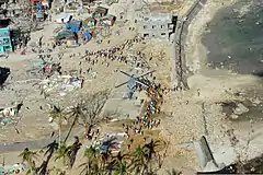 Philippine citizens gather around a U.S. Navy MH-60S Seahawk helicopter